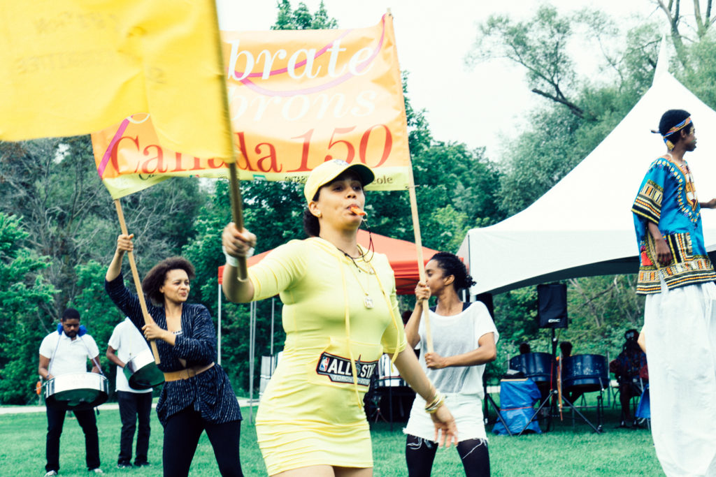A group of women carry bright yellow flags across a field.