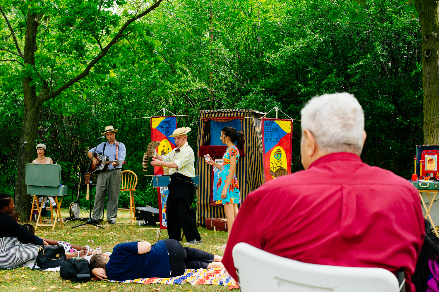 An elderly gentleman is seated and watches performers from a distance.