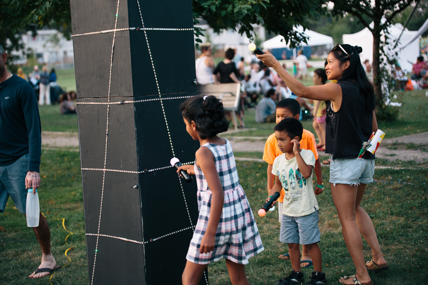 A group of children interact with a large black rectangular sculpture display