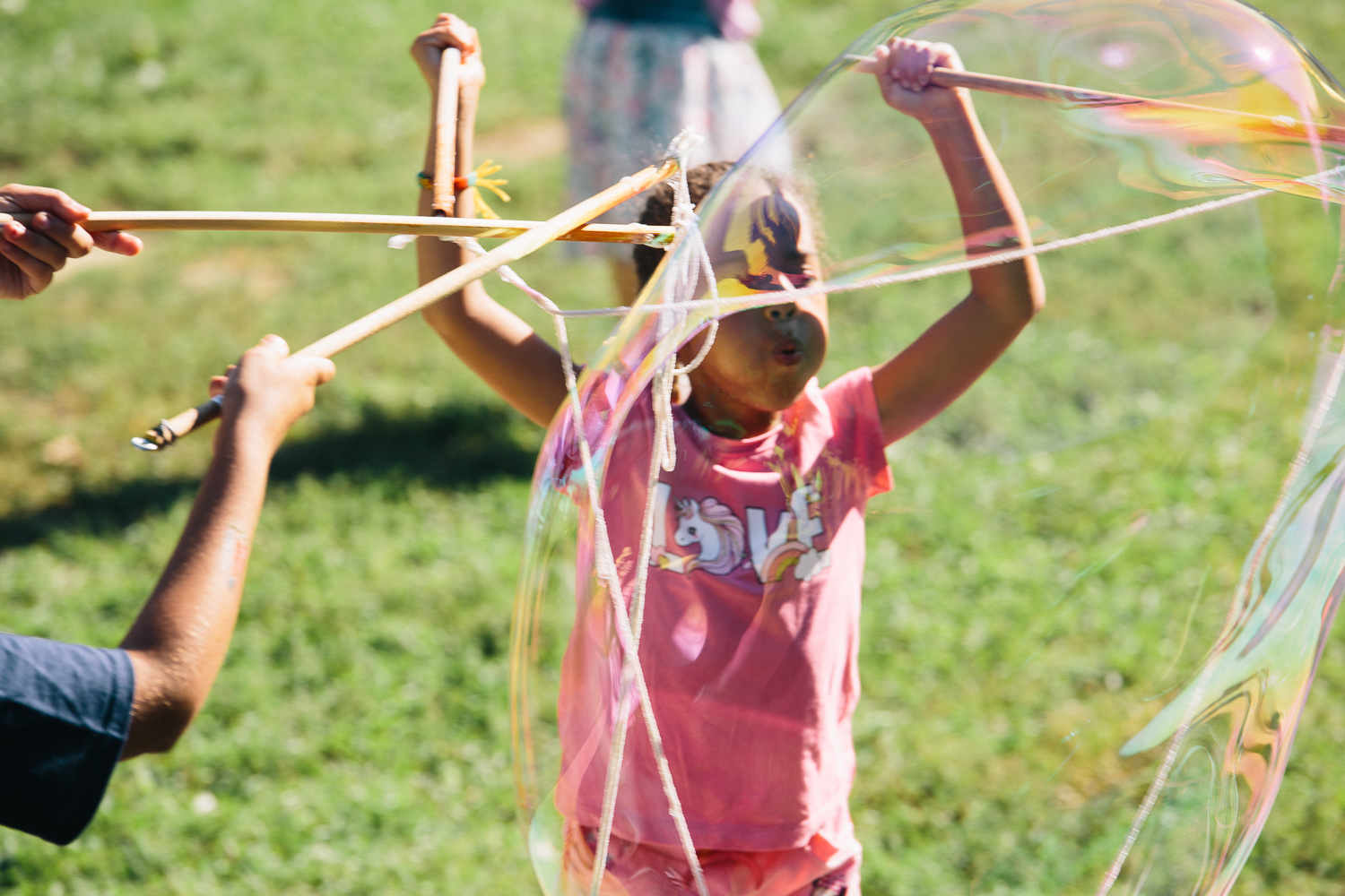 A child uses a stick and rope attached to use large bubbles from a bucket.