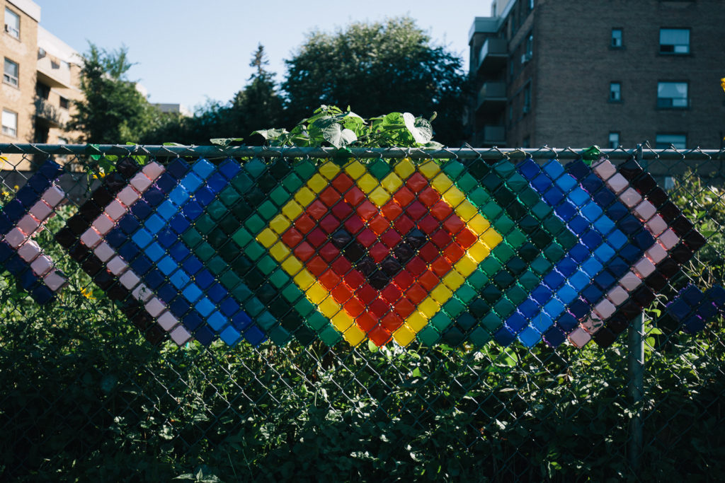 A chain link fence has an image of heart in different colours put together with small blocks.