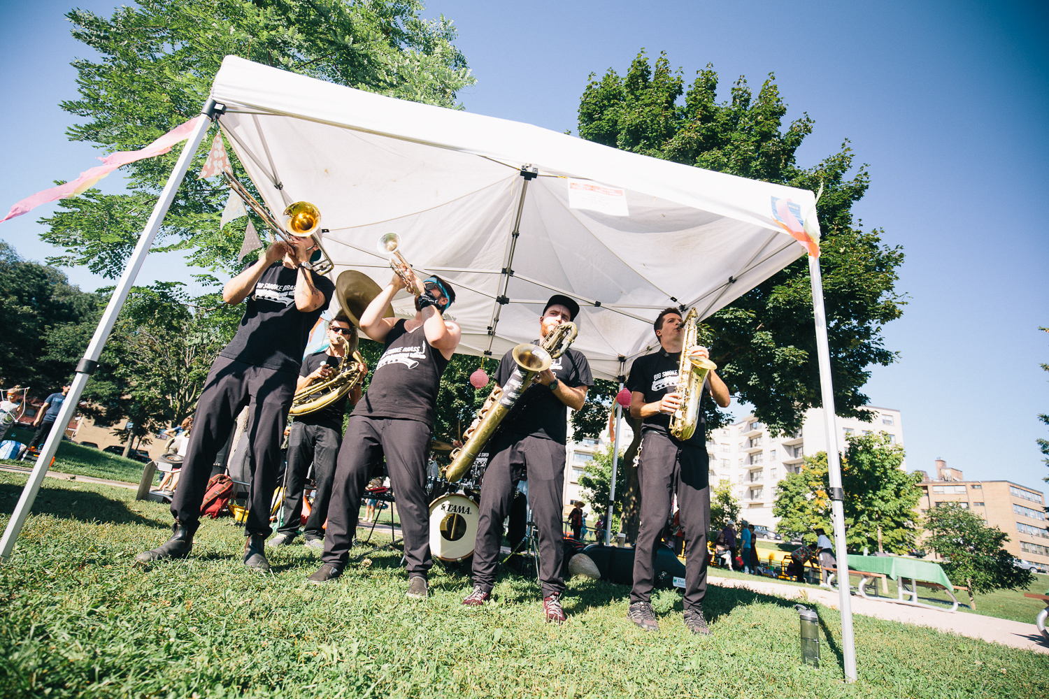 A brass band plays instruments under a white tent.
