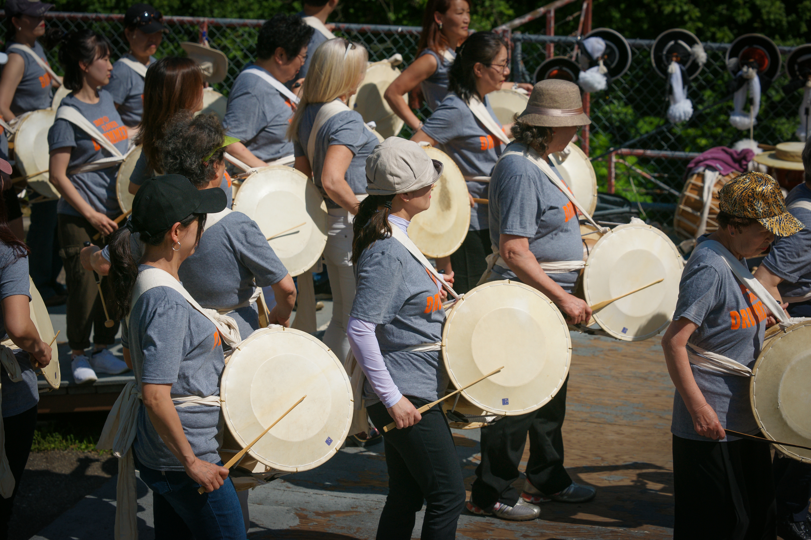 A group of drummers stand and play in unison.