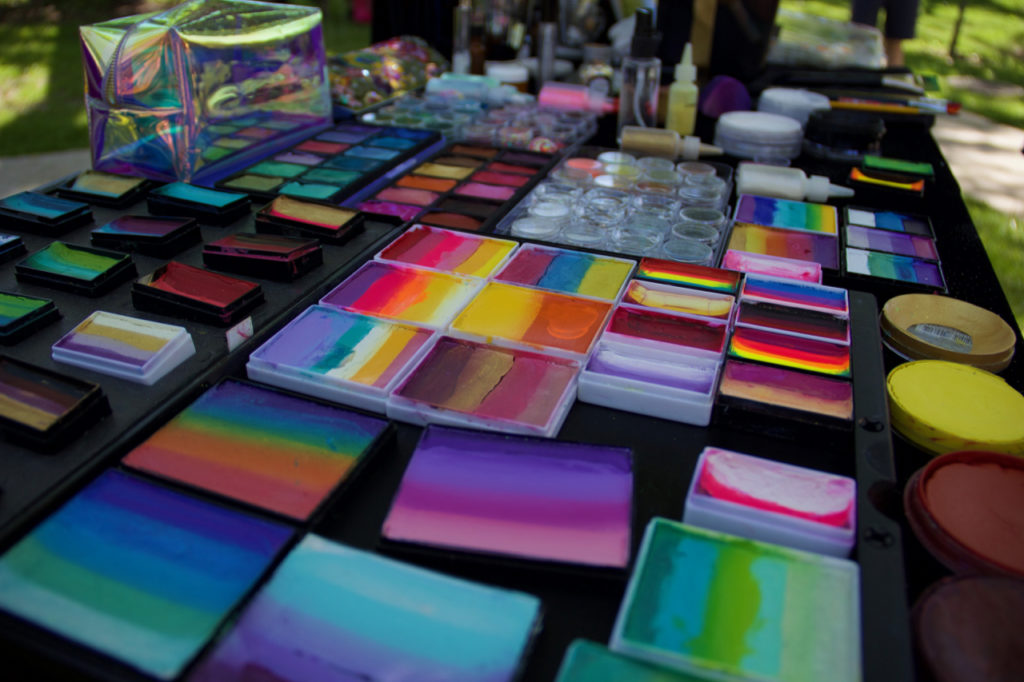 A table covered in many different boxes of multicoloured face paint.