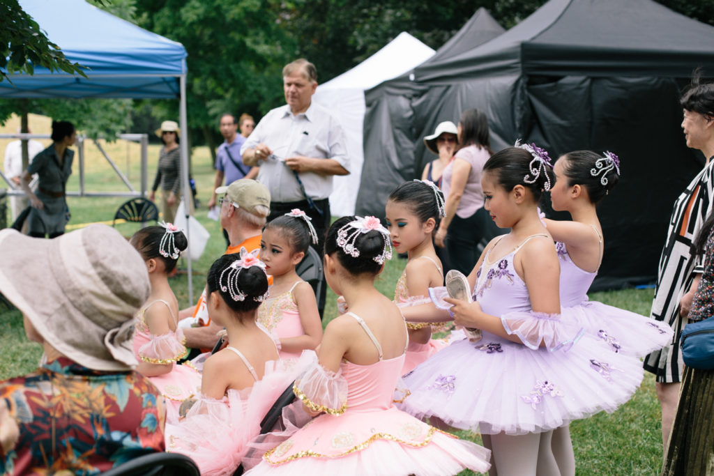 A group of young girls in ballet outfits gathers to get ready for their performance.