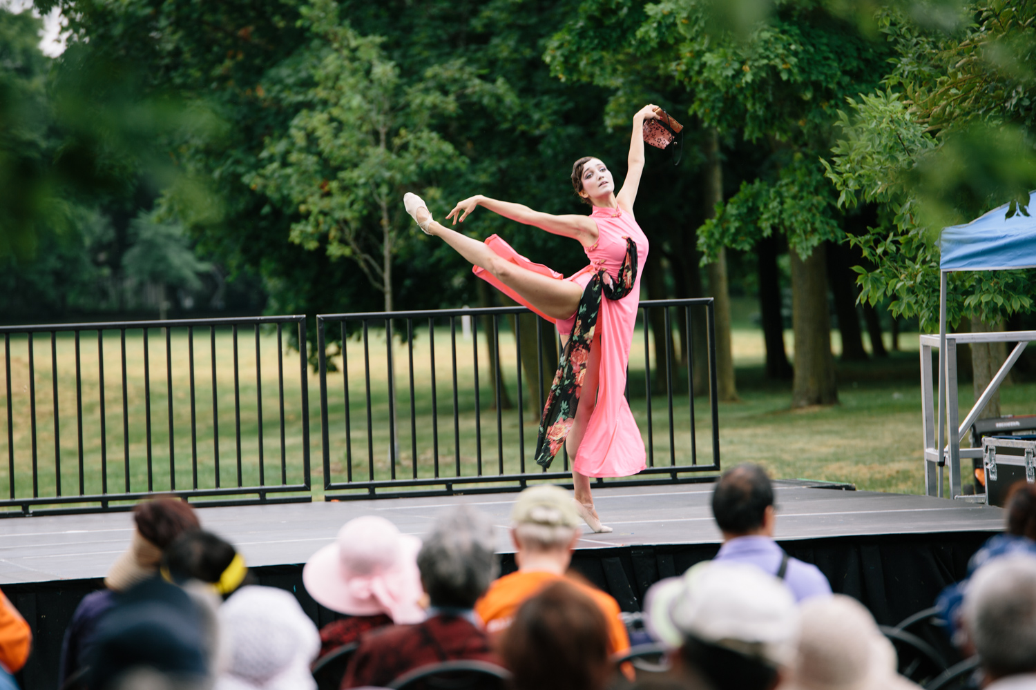 A woman in a pink costume raises her leg as she dances on stage in front of the audience.