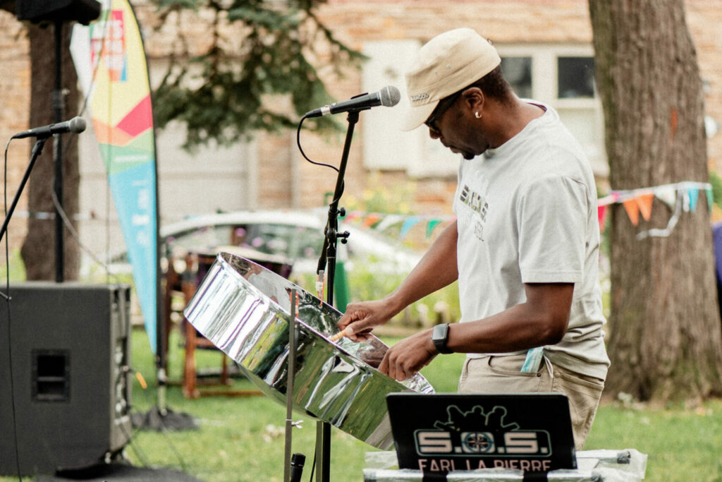 A man in a white shirt plays the steel pan drum.