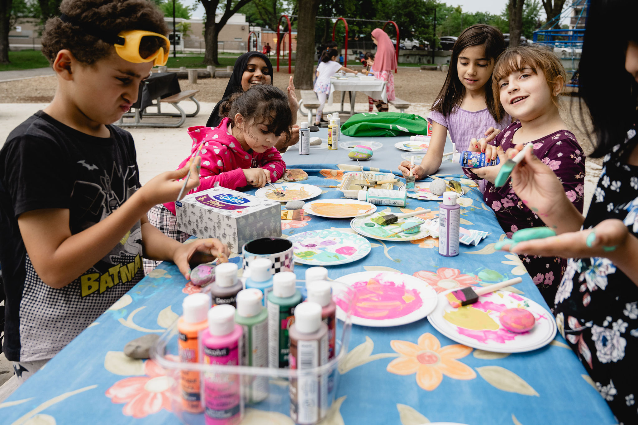 Kids paint at a picnic table in the park.