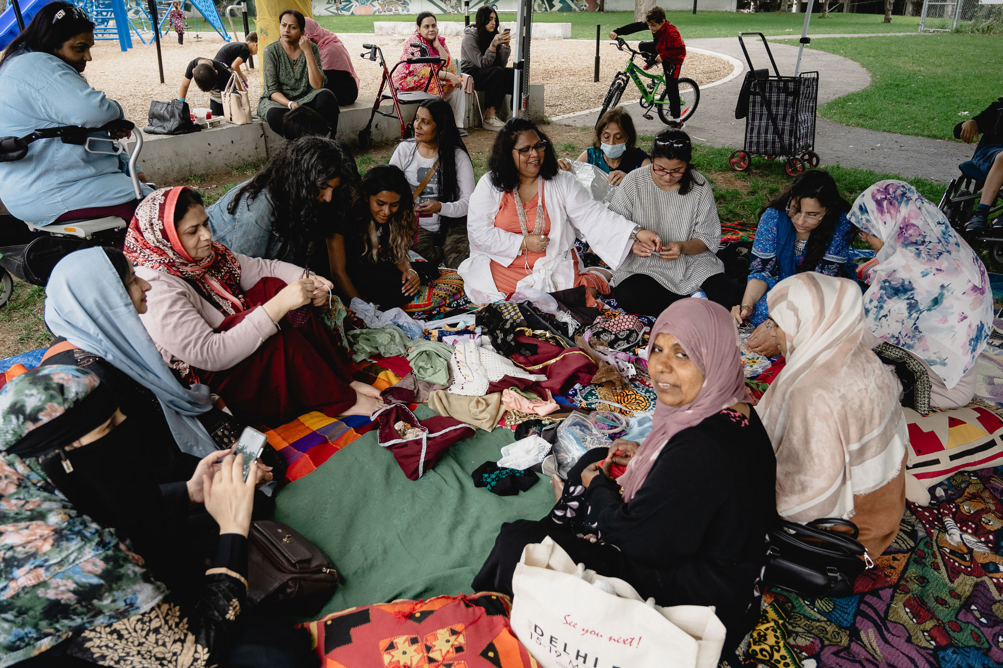 Workshop participants sit in a circle amongst fabrics scraps sewing.
