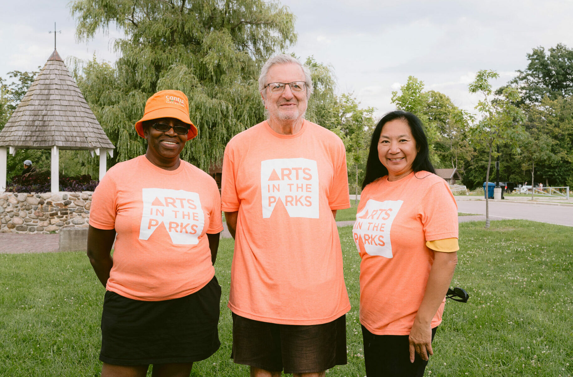 Three Arts in the Parks volunteers with orange t-shirts in the park.