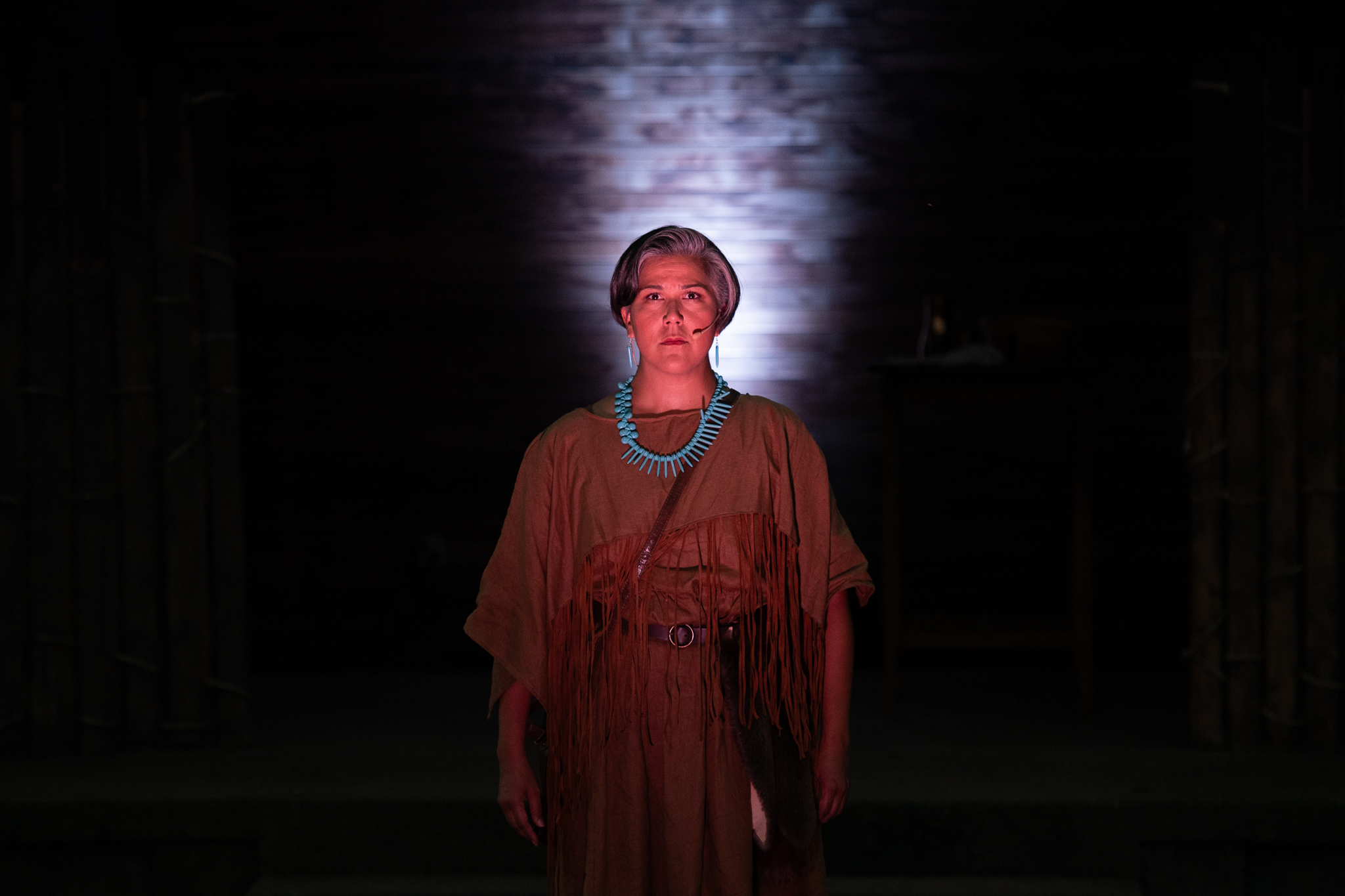 Otîhêw, portrayed by Nicole Joy-Fraser, stands strong surrounded by darkness.